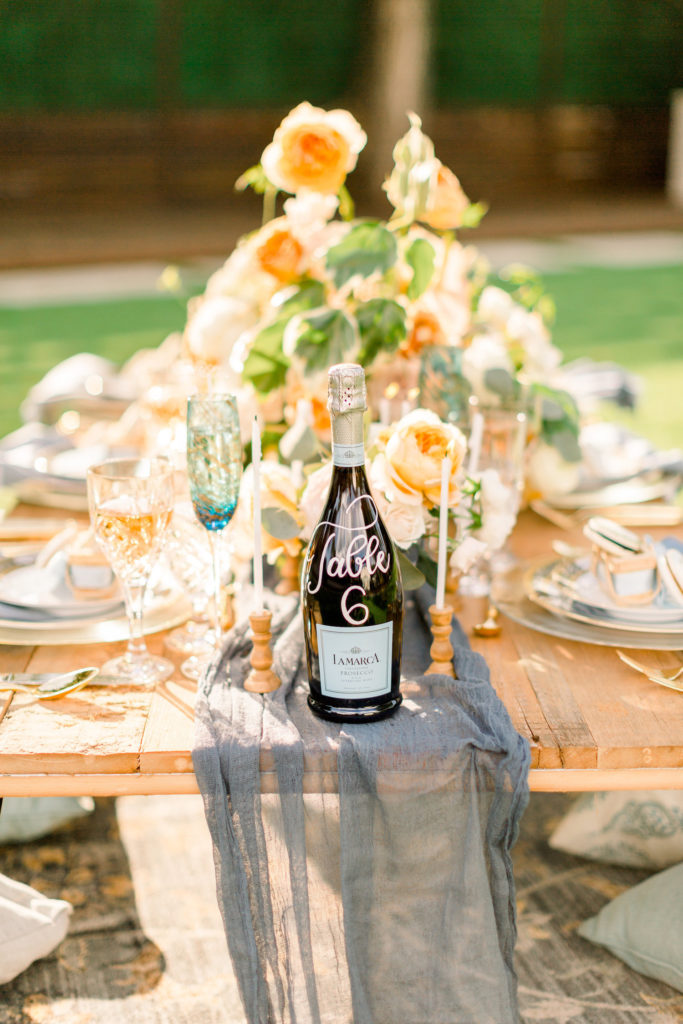 An image of champagne resting on a wooden table decorated with a wedding.