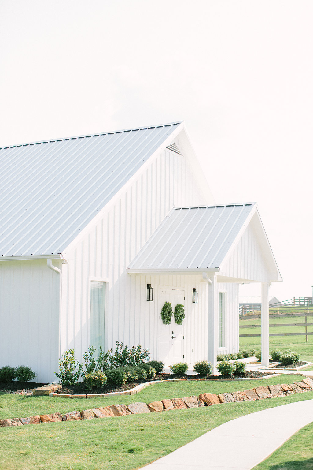 a white barn like wedding venue outside with a green lawn in front by Ellen Ashton Photography
